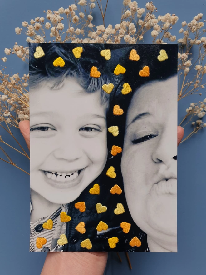 Family photo, with hand embroidered shades of yellow hearts held against blue background