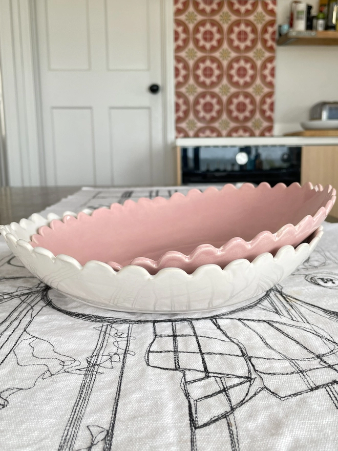 Two stacked serving bowls with scalloped edges on a kitchen table