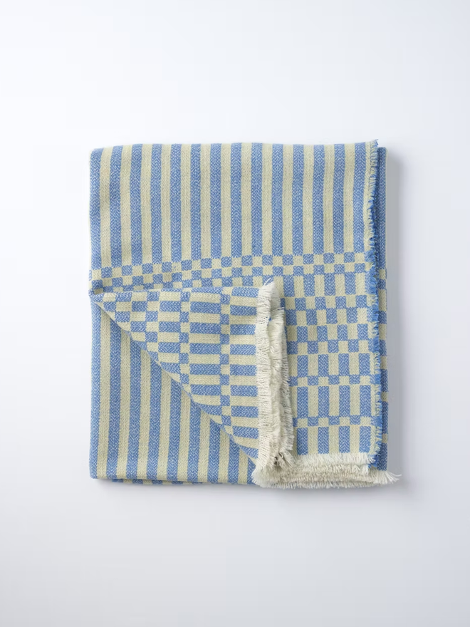 cham lambswool blanket. a blue and yellow striped blanket photographed folded against a white background.