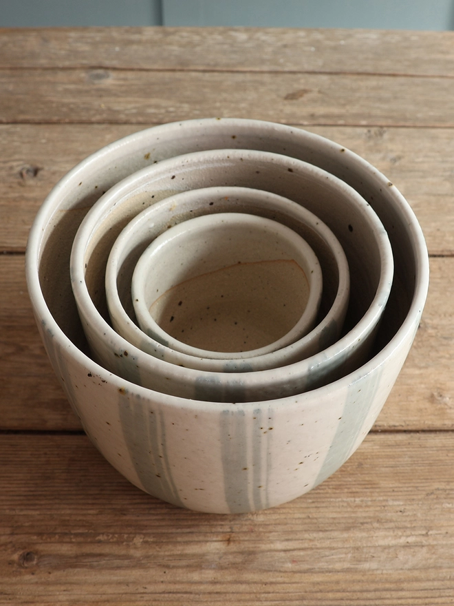 Set of 4 Handmade Ceramic Stoneware Plant Pots in Blue and White Stripe stacked inside each other on a wooden surface. 