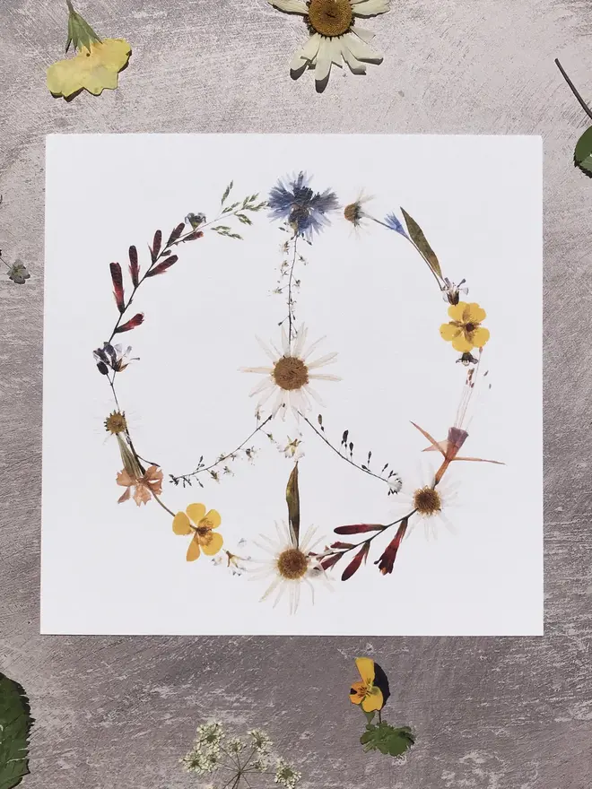 Pressed Wildflower Peace Sign Print, a wildflower peace sign print sitting against a stone surface. 