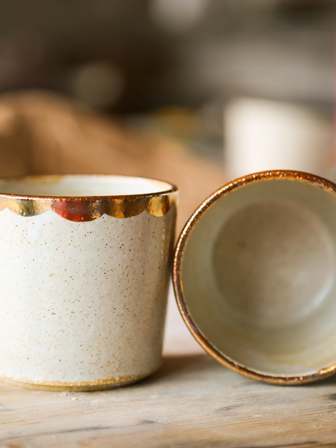 white stoneware drinking beaker with gold scallop decoration around the rim