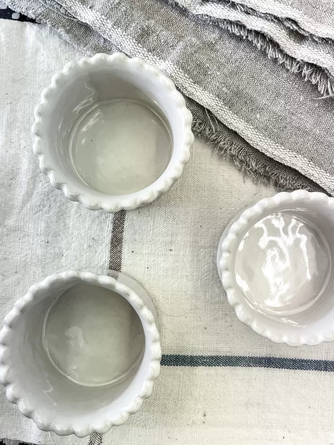 top view of three scalloped edge egg cups in white