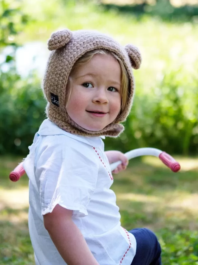 EKA Animal Bonnet seen on a child looking back on a skooter.