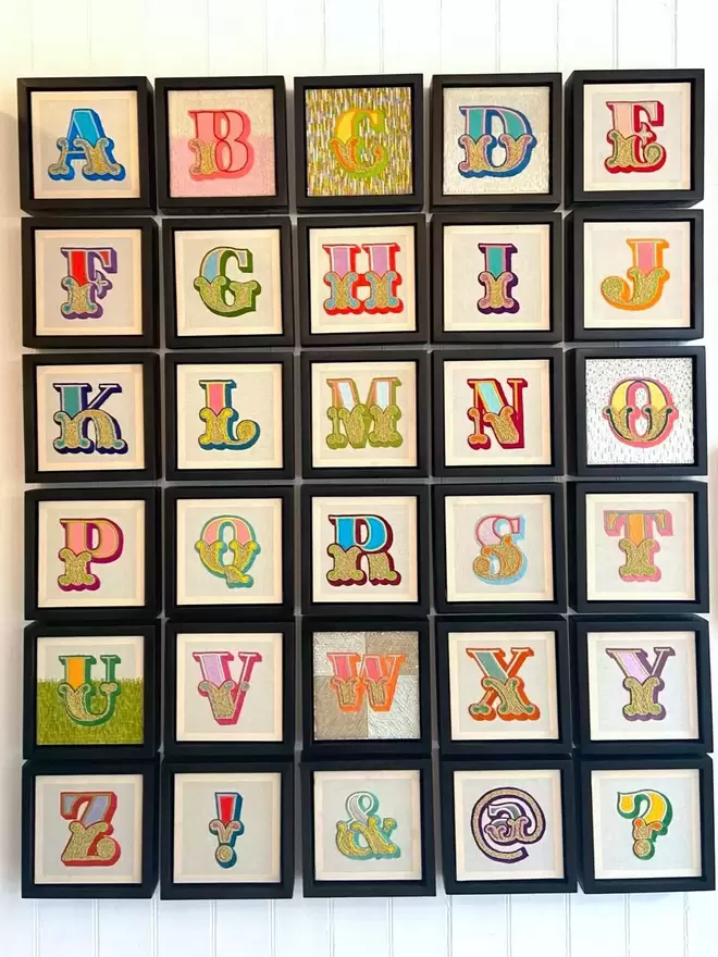 Hand embroidered alphabet individually framed in box frames on a wall 