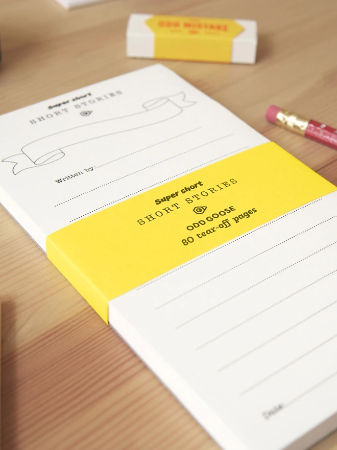 Odd Goose Super Short Stories creative writing notepad seen from top angle with eraser and pencil in background