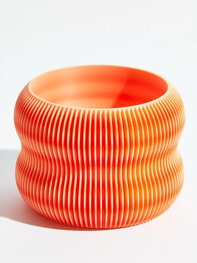 Sustainable 3D Printed Coral Orange Plant Pot, bubble design, against a white background.