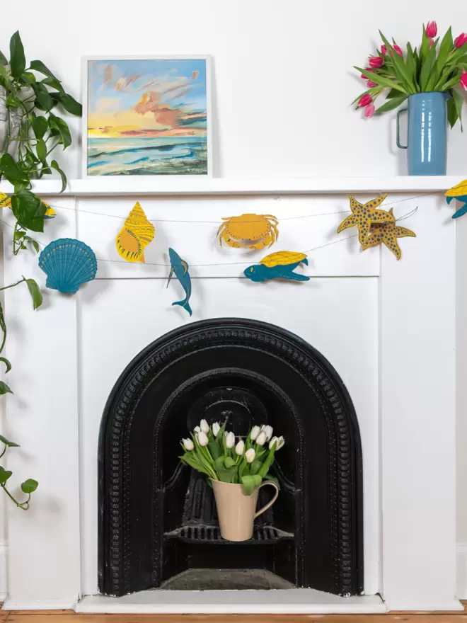 Garland hanging over fireplace with sea shells and fish decorations