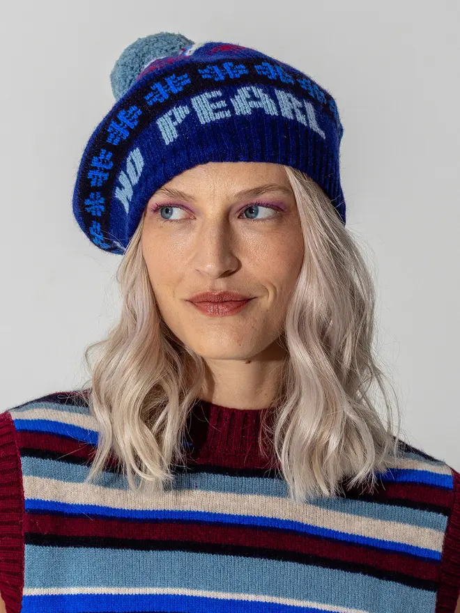 Model wearing the fairisle feminist beret in Klein  featuring the wording No Grit No Pearl