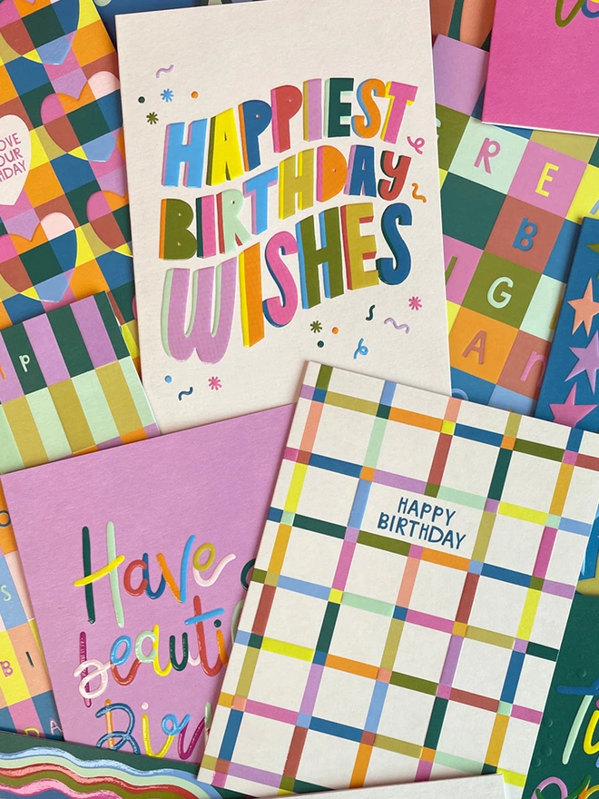 A colourful pile of cards from the Raspberry Blossom ‘Happiness’ greeting card collection. A mix of bold colour blocking, vibrant patterns and bold playful type.