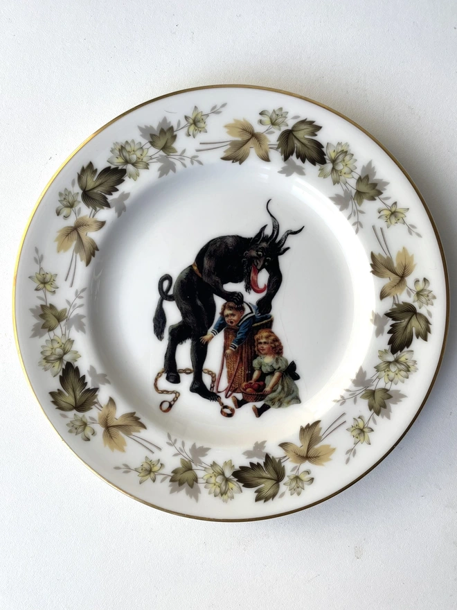 a naughty Christmas Krampus stealing a child, the image is victorian and is printed directly onto an ornate vintage plate