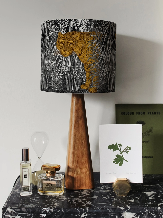 A decorative lampshade featuring an elegant tiger moving through tall tropical grasses, inspired by Henri Rousseau’s jungle paintings, with a rich botanical design.