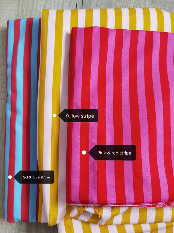merry & bright striped christmas sack. three striped fabric samples in pink, yellow and blue.