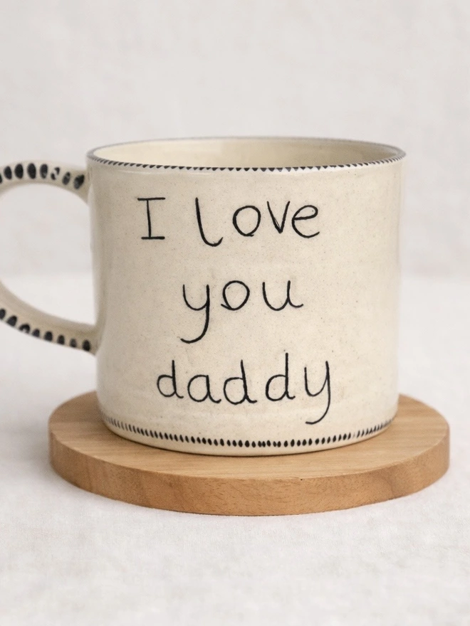 Ceramic mug with a child's writing saying 'I love you daddy' on it 