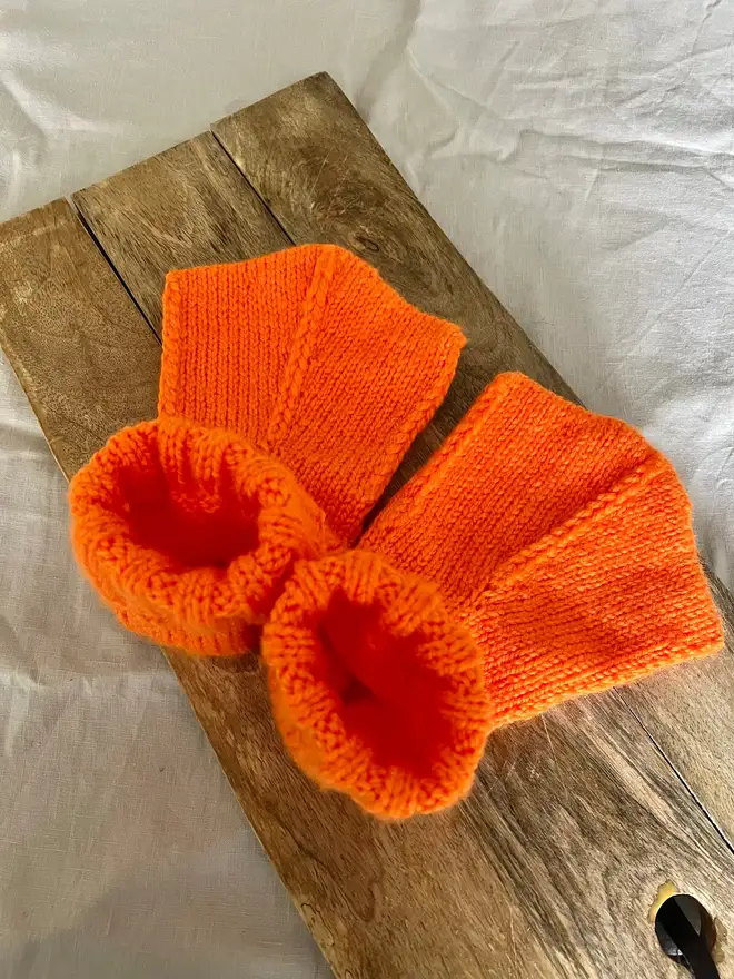 Duck Feet Socks, a pair of orange duck feet socks sitting on a wooden board. 