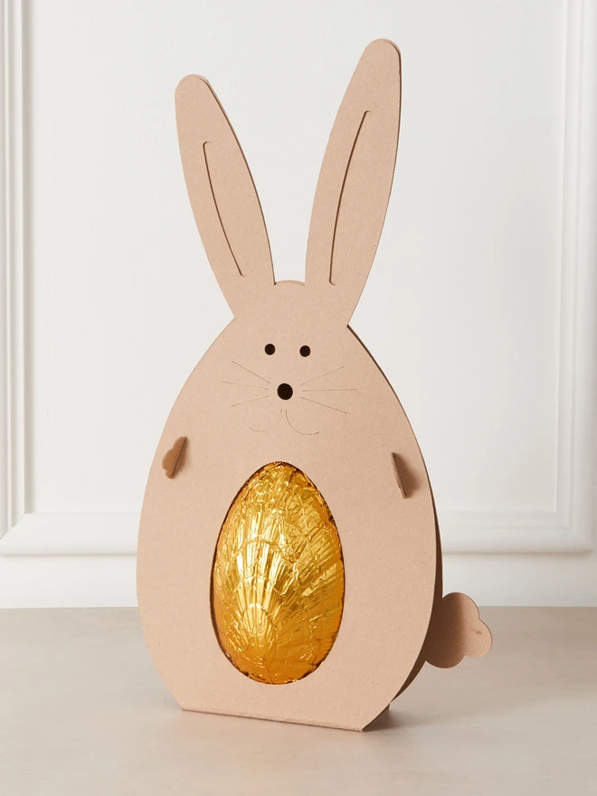 salted caramel milk chocolate easter egg. a chocolate egg photographed in gold foil within a cardboard rabbit.
