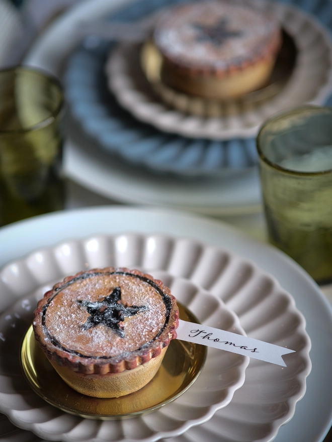 A festive handpainted wooden mince pie place setting with handwriten note to welcome your guests at the Christmas table
