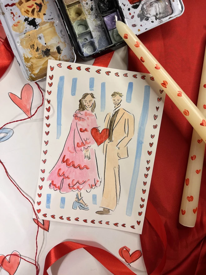 A hand-painted A5-sized personalised portrait of two people by Eleanor Joanna, illustrated in a whimsical style. The background is fully customisable to reflect the buyer's preferences, making it a unique and tailored piece of art. Valentines background with hearts dotted around the edge of the portrait.