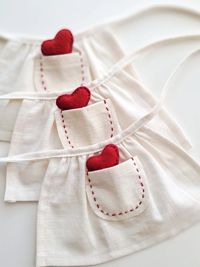 Close-up of a handmade linen apron with hand-stitched pocket and red felt heart detail for Veronica Bunny