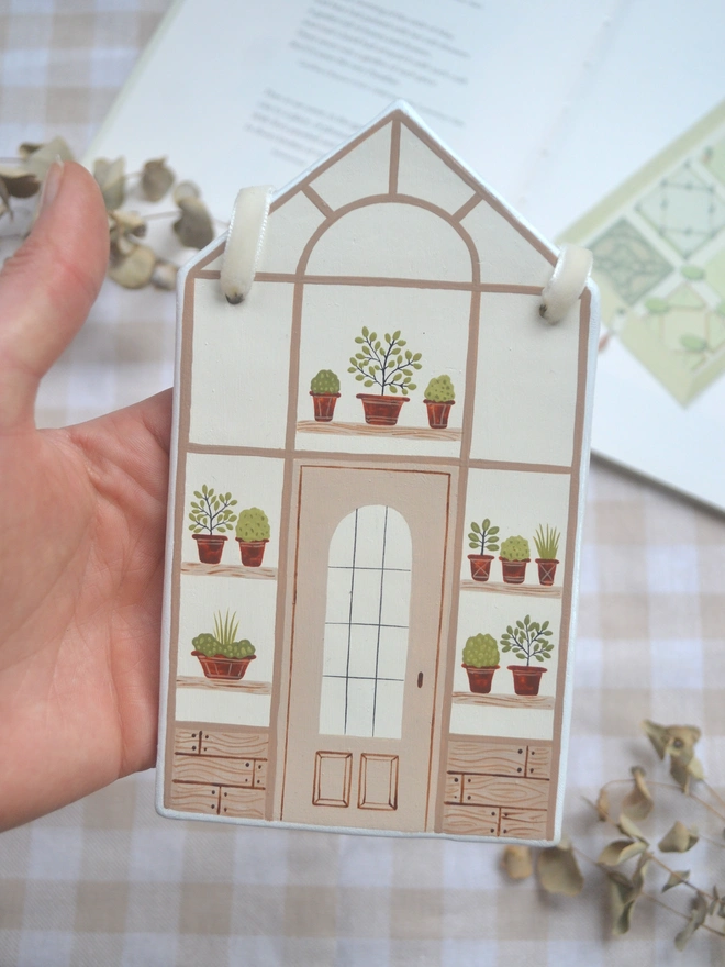 white ceramic hanging decoration with brown greenhouse illustration design