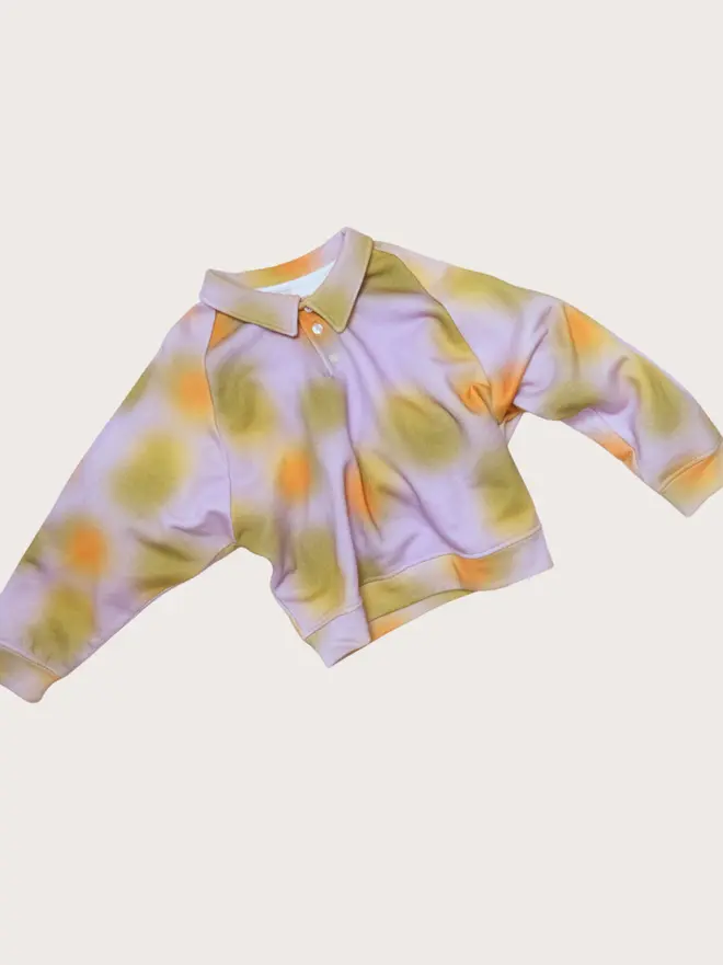 Front flat lay of the Studio Koter Luka jersey top in Hazy Lilac, a soft-print sweatshirt with a buttoned collar and dropped shoulders.