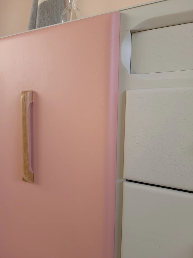 Close up pink painted cabinet door on a beige painted sideboard