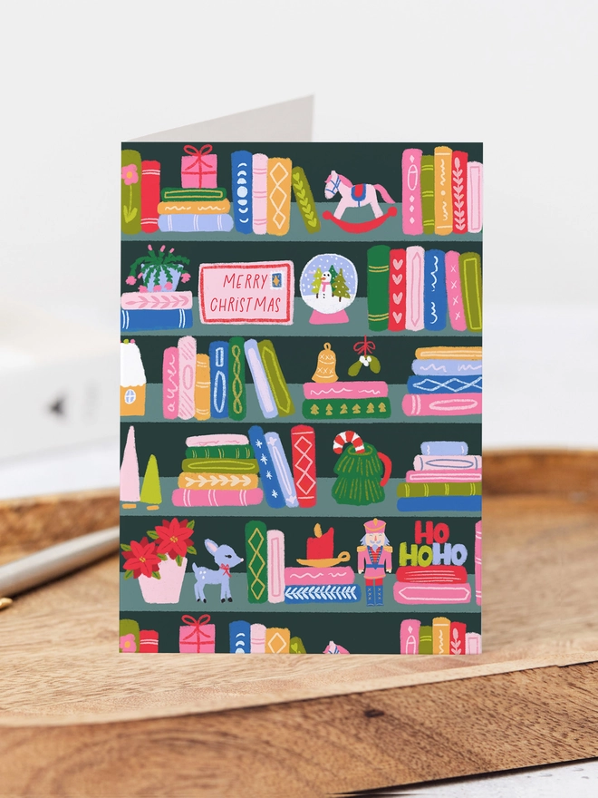 A standing open card featuring a Christmas bookshelf illustration.