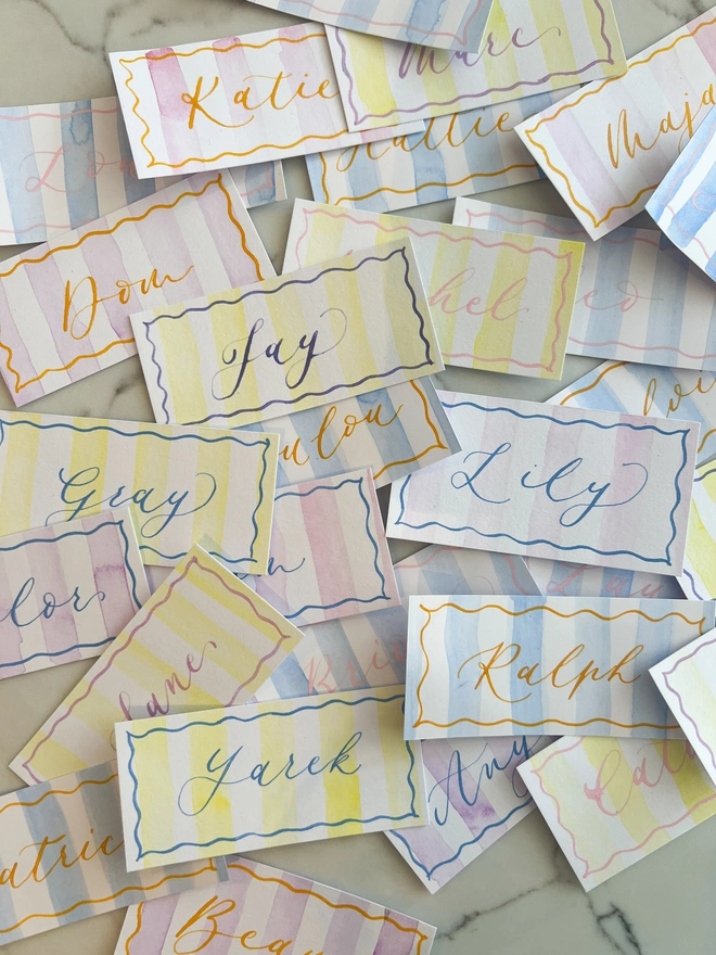 Personalised calligraphy event place cards, striped coloured place cards spread together