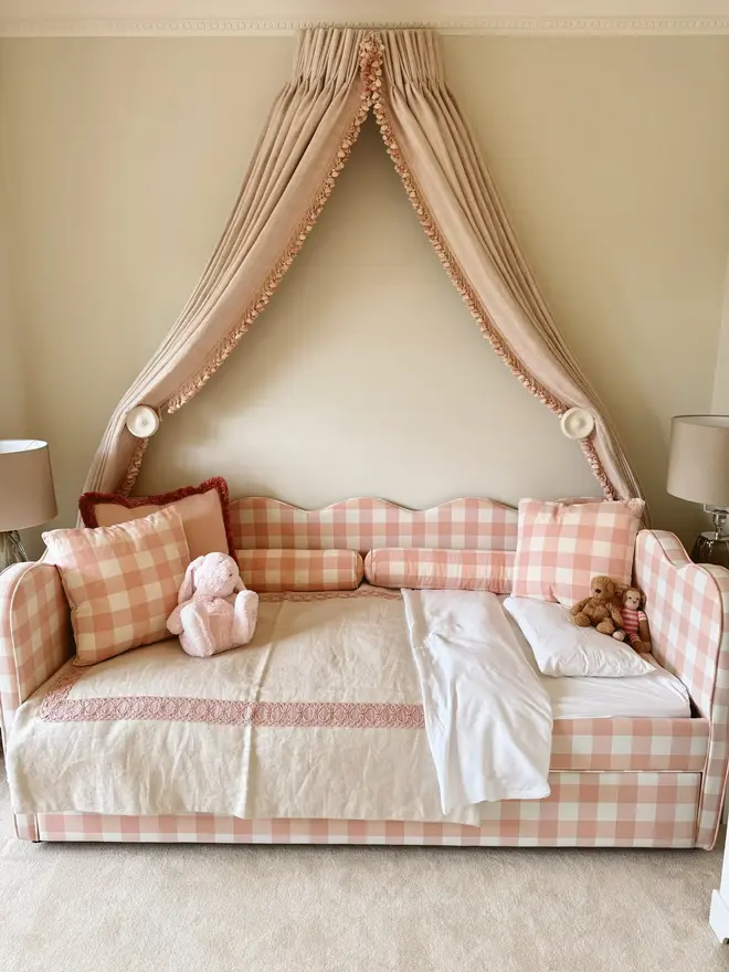 'The Lochlan' upholstered gingham trundle bed. a pink gingham children's sofa-style bed with cushions and a duvet.
