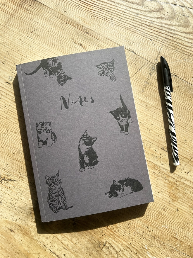 Pussycat notebook with a pen next to it.