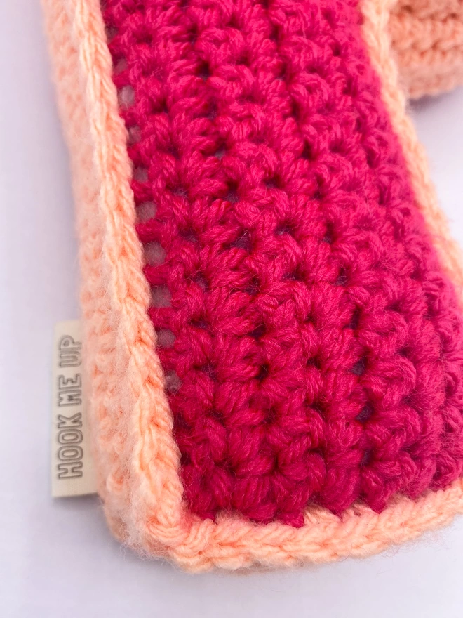 Crocheted P Cushion in Raspberry and Peachy Pink, close up of label