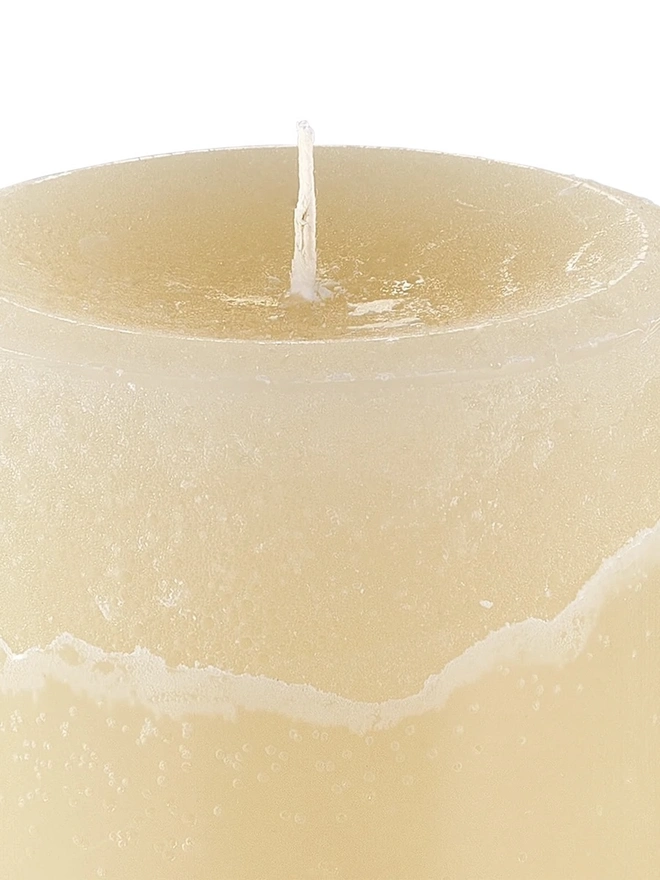 Jasmine, Green Tea & Mulberry Candle (Set Of 1 Or 3 Wicks). a close-up shot of the oudh, yuzu and patchouli candle shows the top of the cream wax pillar, with a single wick and a textured, slightly uneven surface. drip marks run down the side of the candle, adding to its handmade, rustic finish. the plain white background keeps the focus on the wax texture and colour.