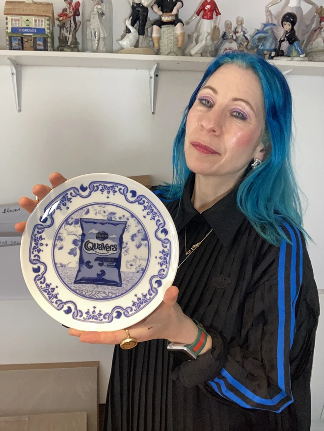 Blue and white Delft style decorative plate featuring a packet of Quavers crisps in the centre.