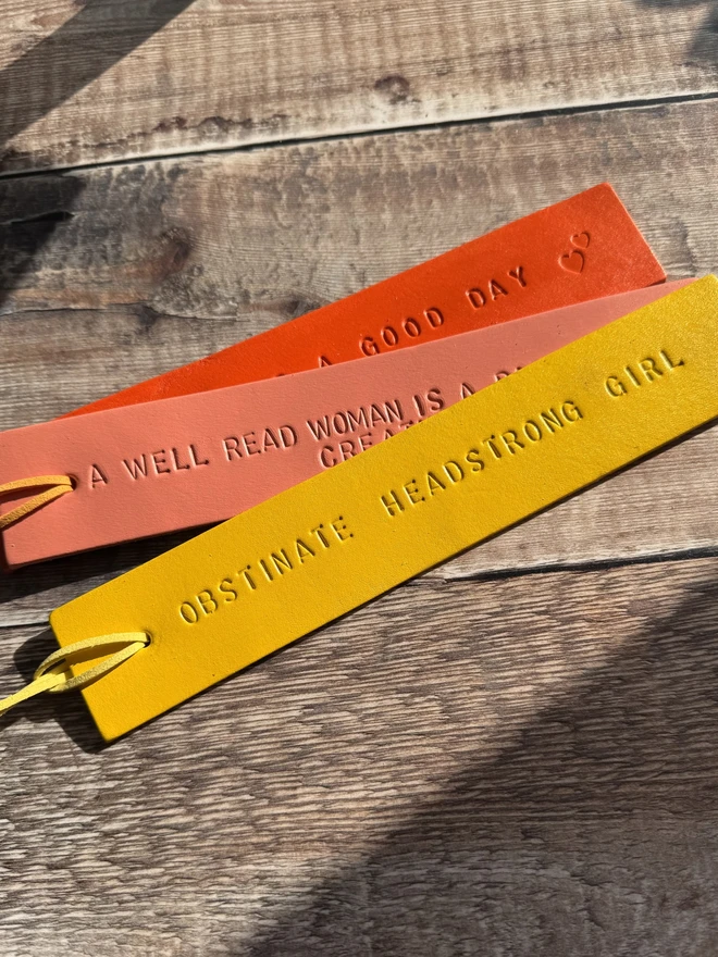 Colourful hand-painted leather bookmarks with embossed quotes, each featuring a leather tie. A stylish and durable accessory for book lovers, perfect as a personalised gift