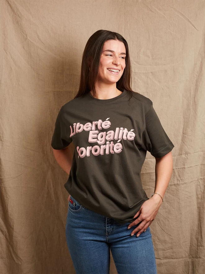 Model is wearing a charcoal grey cotton t-shirt with the slogan Liberté, Egalité, Sororité in pale pink written on the front