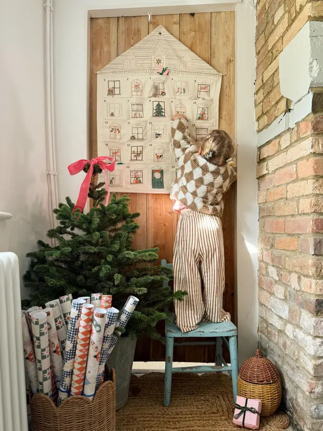 Fabric Christmas House Advent Calendar, with a little girl putting in a present. 