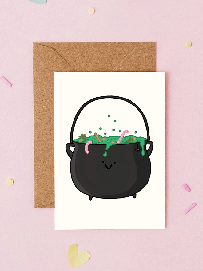 Hand drawn mini Halloween card featuring a smiling black witch's cauldron bubbling with green potion and worms. Cute spooky greeting card by You've Got Pen On Your Face.