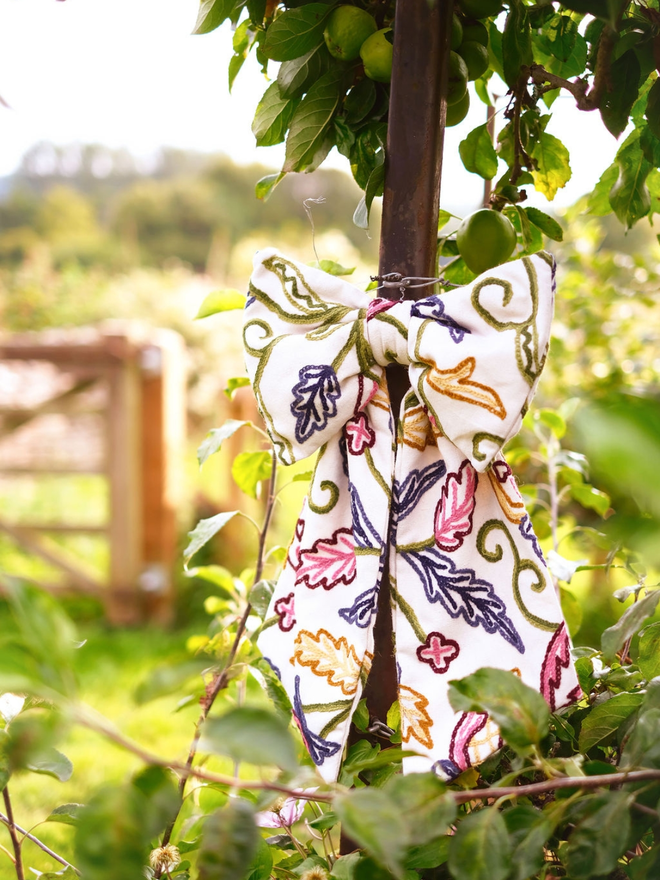 Large decorative bow made with red, blue and green embroidered botanical vintage crewel fabric. 