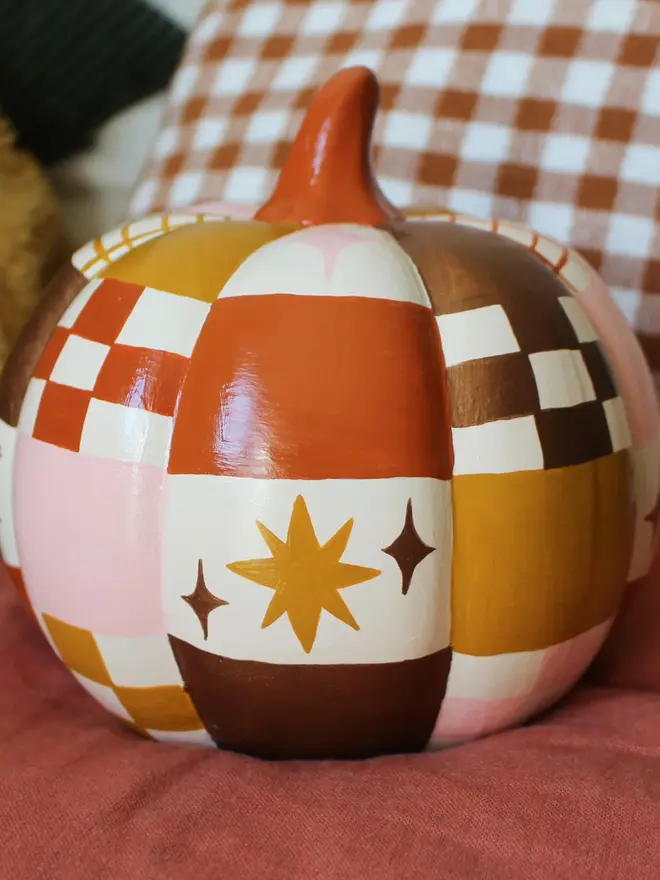 hand-painted celestial patchwork ceramic pumpkin. a ceramic pumpkin painted with patchwork colours of gold, pink, brown and stars and moons.