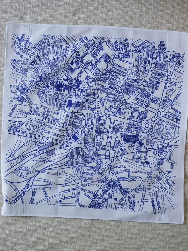 A Mr.PS Leeds map hankie printed in blue laid flat on a linen tablecloth