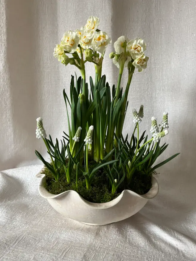 Large Frilly Bowl - Pearl holding green and white flowers on white cloth background