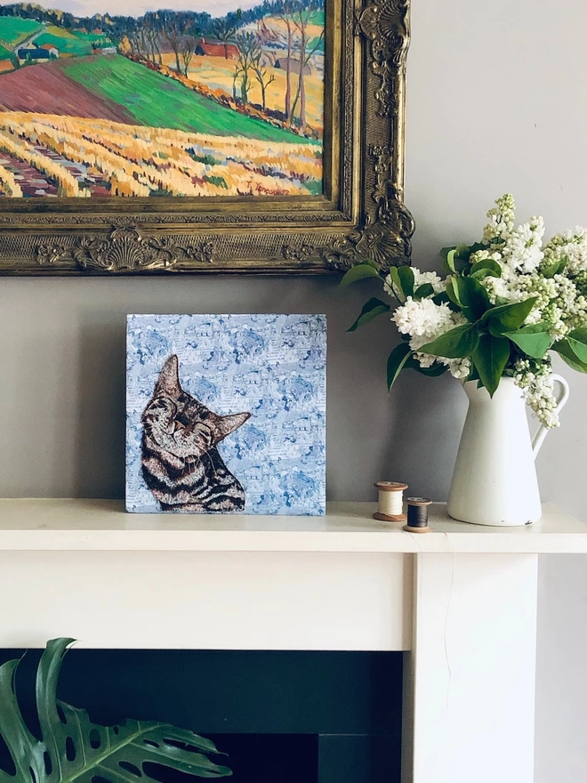 Photo of a large embroidered pet portrait of a basking cat in its home