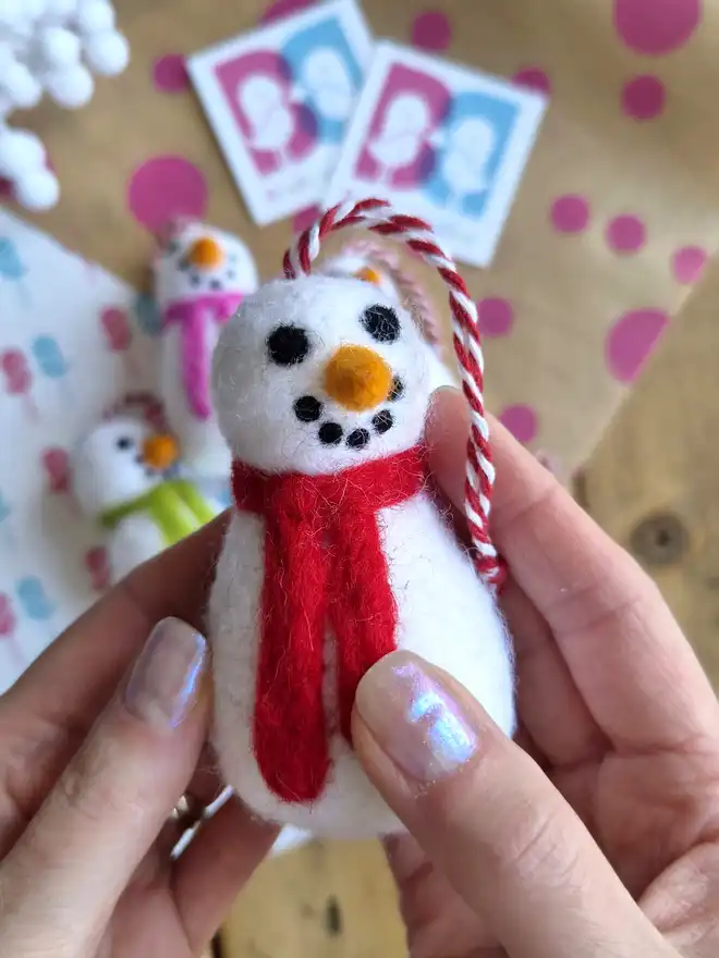 A felt snowman hanging Christmas tree decoration, with a red scarf around it's neck.