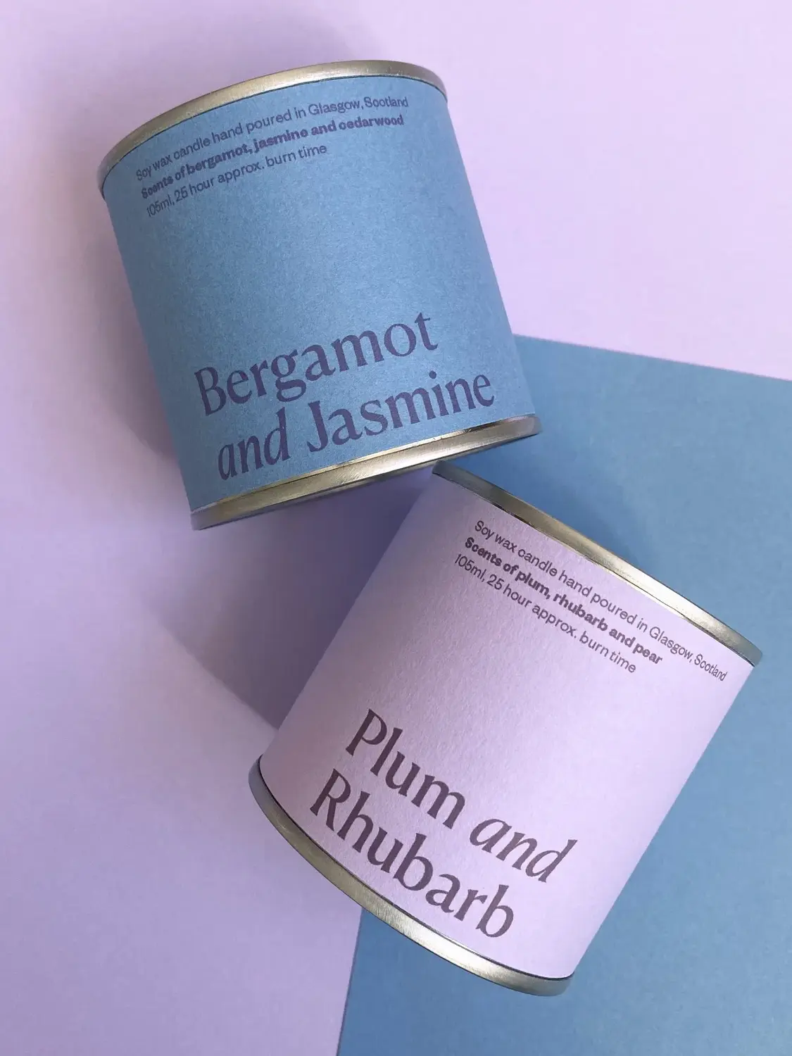 lum & Rhubarb Soy Wax Candle Tin, against a purple and blue background. 