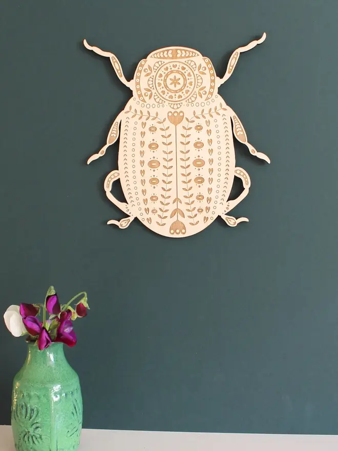Folk Art Beetle Wall Hanging, wooden insect decoration hanging on a wall. 