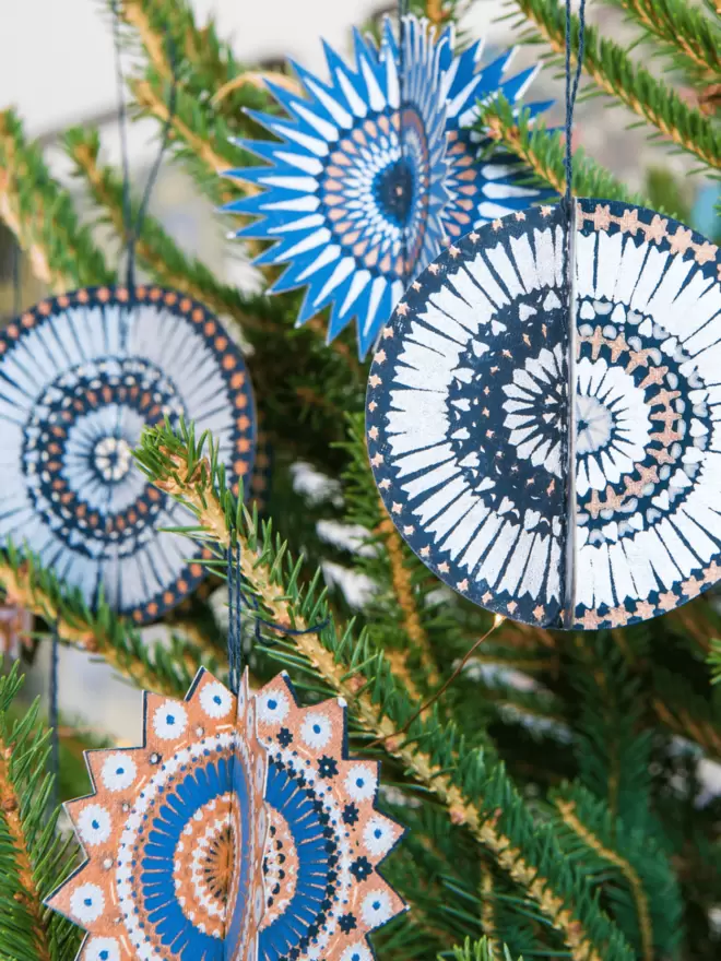 Close-up, detailed shot: 4 blue and silver star decorations hanging on tree