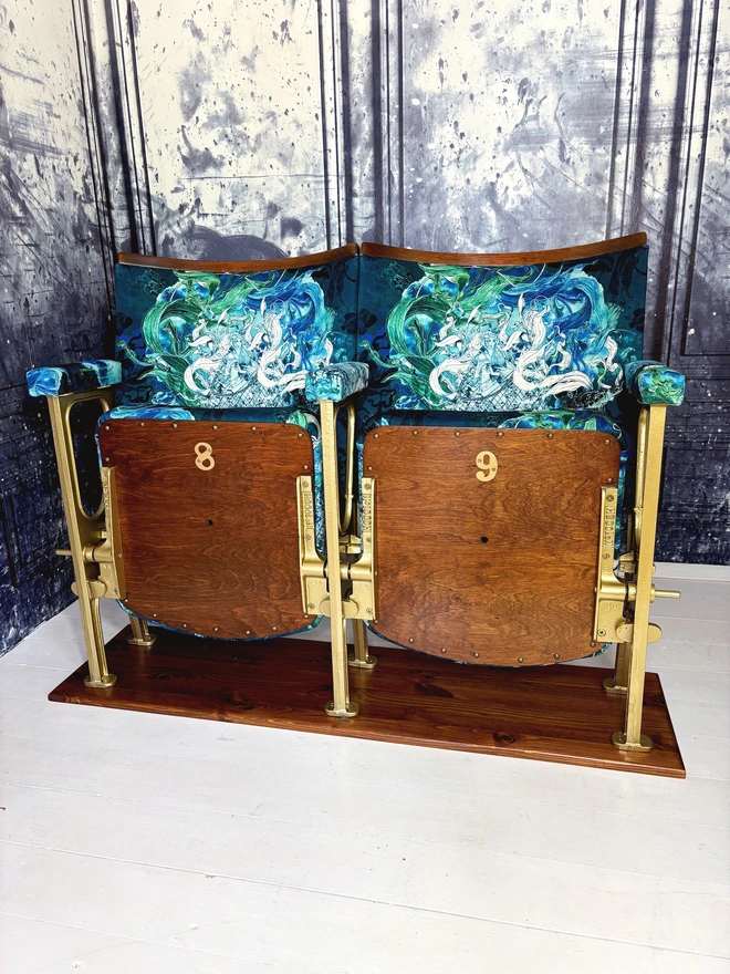 Set of two vintage cinema seats with seats closed, on a white wooden floor against a blue marbled wall