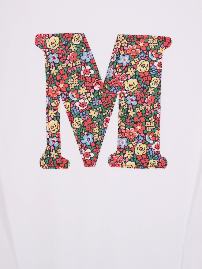 a personalised kids white t-shirt with an initial cut from liberty floral print appliqued on the front