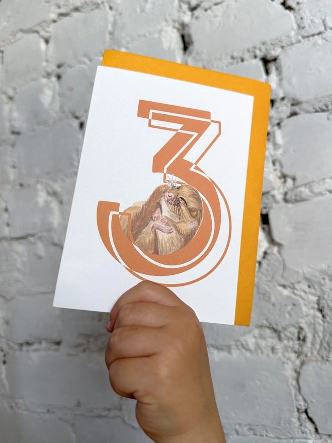 a white card with a big orange number 3 and an illustrated dormouse with a bright yellow envelope
