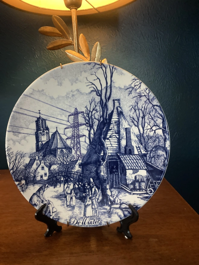 Vintage blue & white Delft plate featuring a winter scene and a pylon.